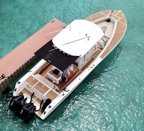 Top view of a motorboat docked on clear turquoise water.