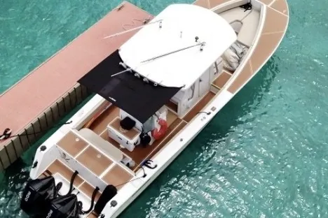 Top view of a motorboat docked on clear turquoise water.